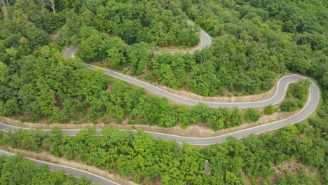 large rv driving down a narrow, winding mountain road with several switchbacks on a sunny summer day