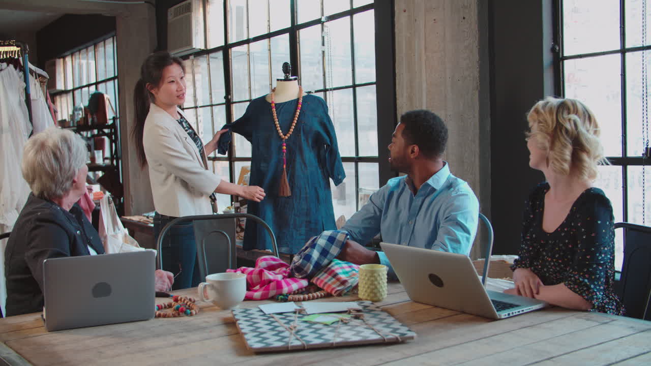 네 명의 패션 디자이너 들 이 옷 을 논의 하고 있다