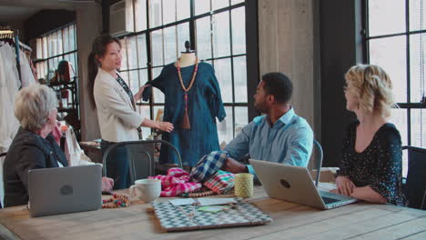 cuatro diseñadores de moda en una reunión discutiendo prendas de vestir