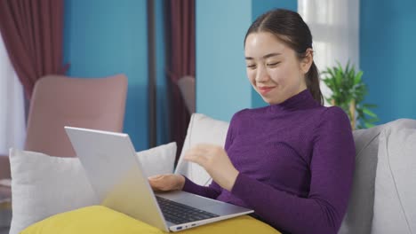 Die-Süße-Asiatische-Frau-Schaut-Sich-Einen-Film-Auf-Dem-Laptop-An,-Genießt-Und-Lacht.