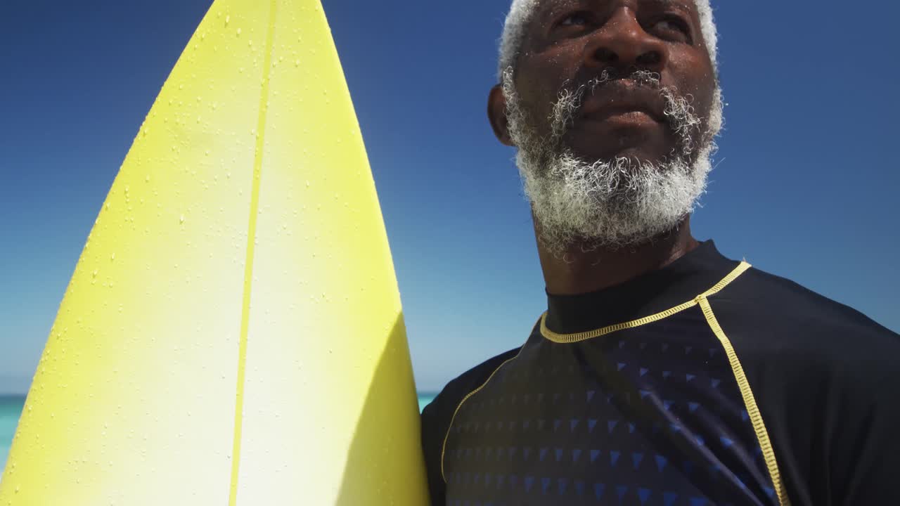 hombre mayor con una tabla de surf en la playa