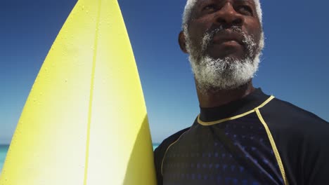 senior man with a surfboard at the beach