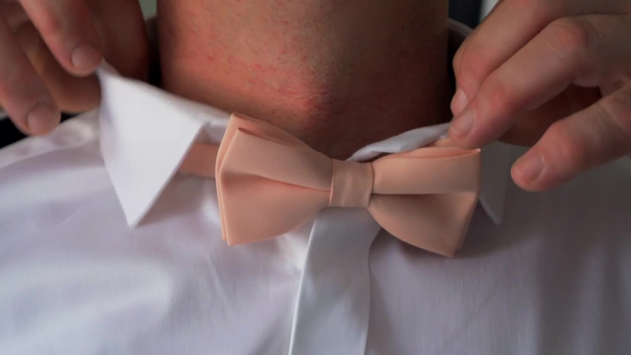 Novio ajustándose una pajarita beige antes de la ceremonia de la boda