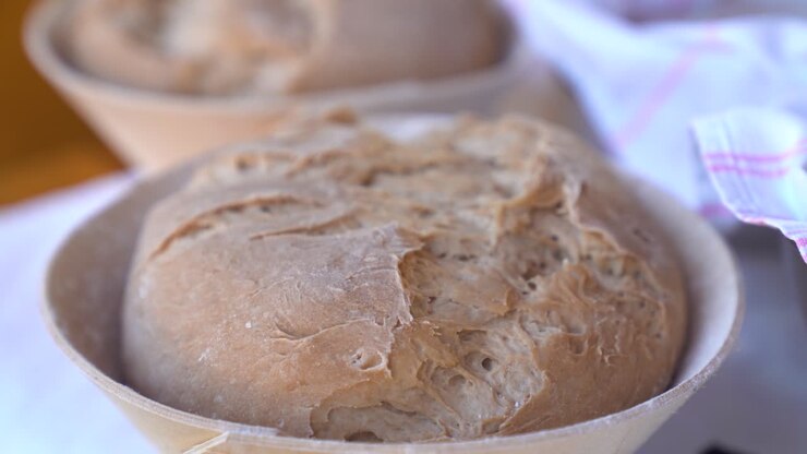 Freshly baked bread dough resting in proofing baskets in a warm, rustic kitchen