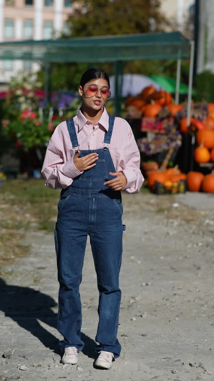 mujer en mono y camisa rosa en un mercado al aire libre