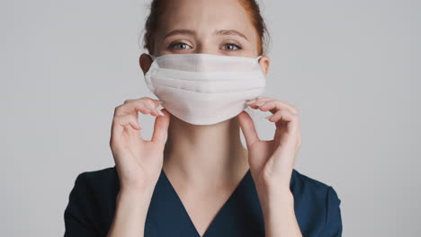 redheaded nurse in front of camera on gray background.