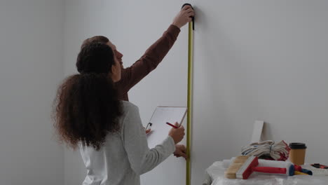 couple measuring wall for home renovation project