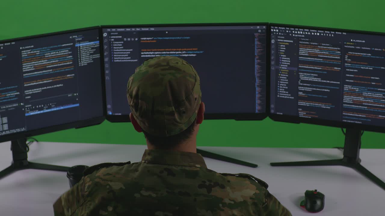 Back View Of Tired Asian Man Soldier Developer Stretching While Write Code With Multiple Computer Screens In Green Screen Studio