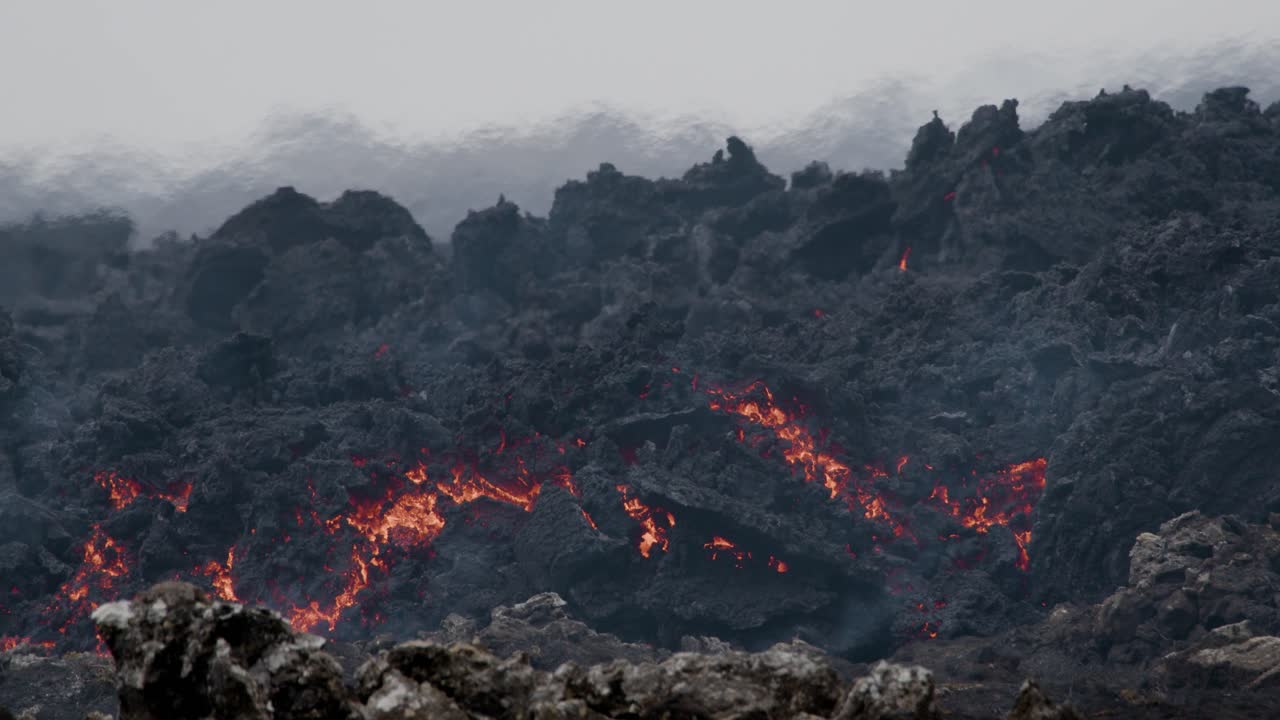 flujo de lava derretida del volcán grindavik en islandia, que muestra grietas brillantes y corteza de lava oscurecida