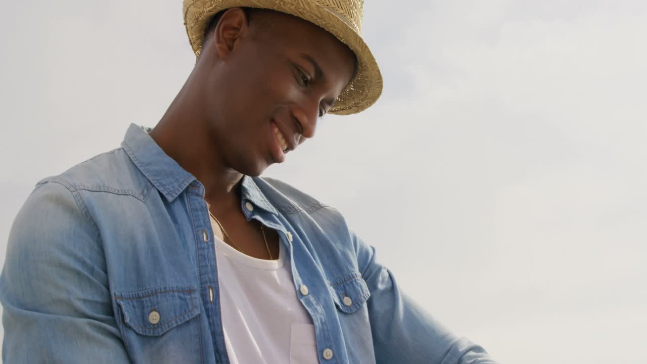 해변에서 스마트 워치를 사용하는 아프리카계 미국인 남자의 낮은 각도 뷰 4k