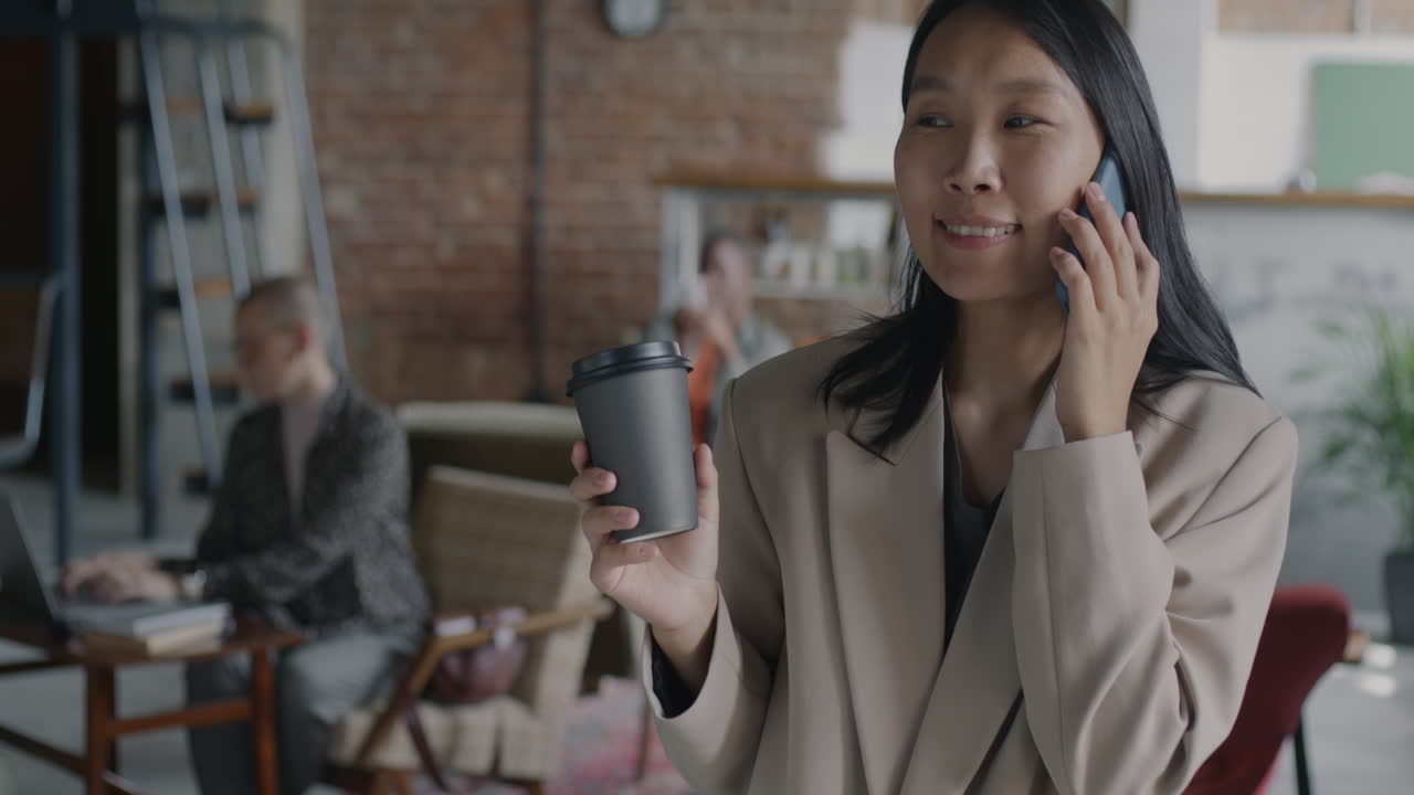 Mulher Falando ao Telefone e Tomando Café no Escritório