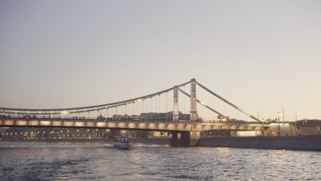 evening cityscape view of a cable-stayed bridge over a river with a boat