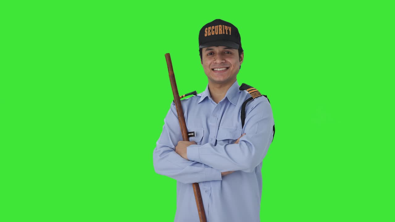 Ritratto di una felice guardia di sicurezza indiana in piedi a braccia conserte. Schermo verde