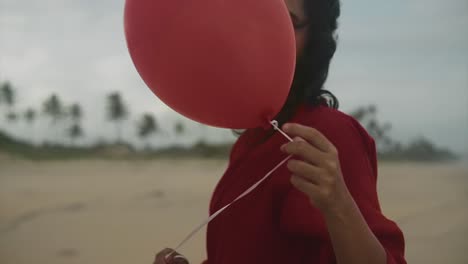 retrato de una joven hermosa mujer india sosteniendo un globo en la mano con la playa y las palmeras en el fondo