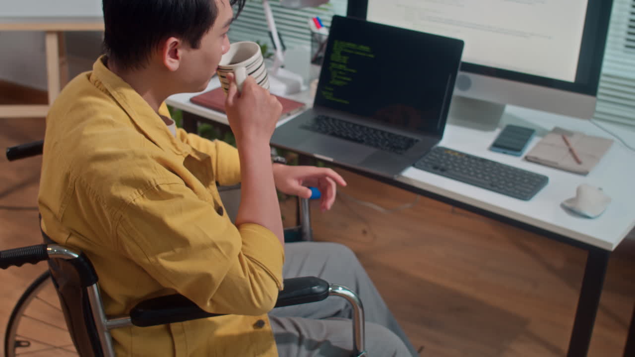 Male Developer in Wheelchair Drinking Coffee when Coding at Office