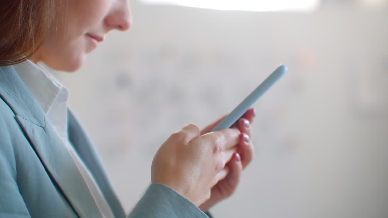 젊은 여성 디자이너, 옷차림 스튜디오에서 드폰을 들고, 바느질 작업실에서 고객에게 메시지를 쓰는