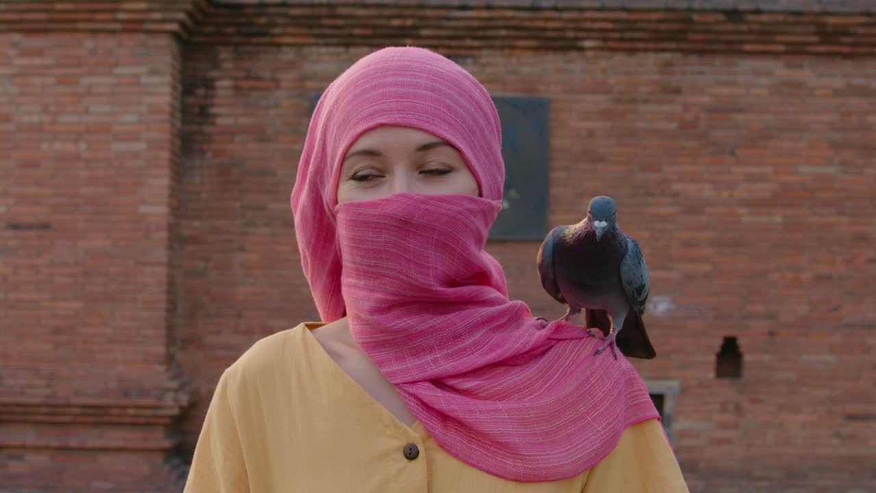 Woman in Pink Hijab with Pigeon on Shoulder