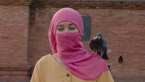 woman in pink hijab with pigeon on shoulder