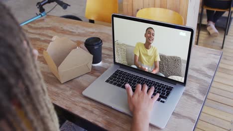 frau, die einen snack isst, während sie einen videoanruf auf dem laptop im café macht