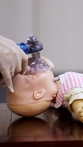 demonstration of cpr on a baby model. instructor in medical gloves showing the right breathing exercise on a dummy in training center. side view. vertical video