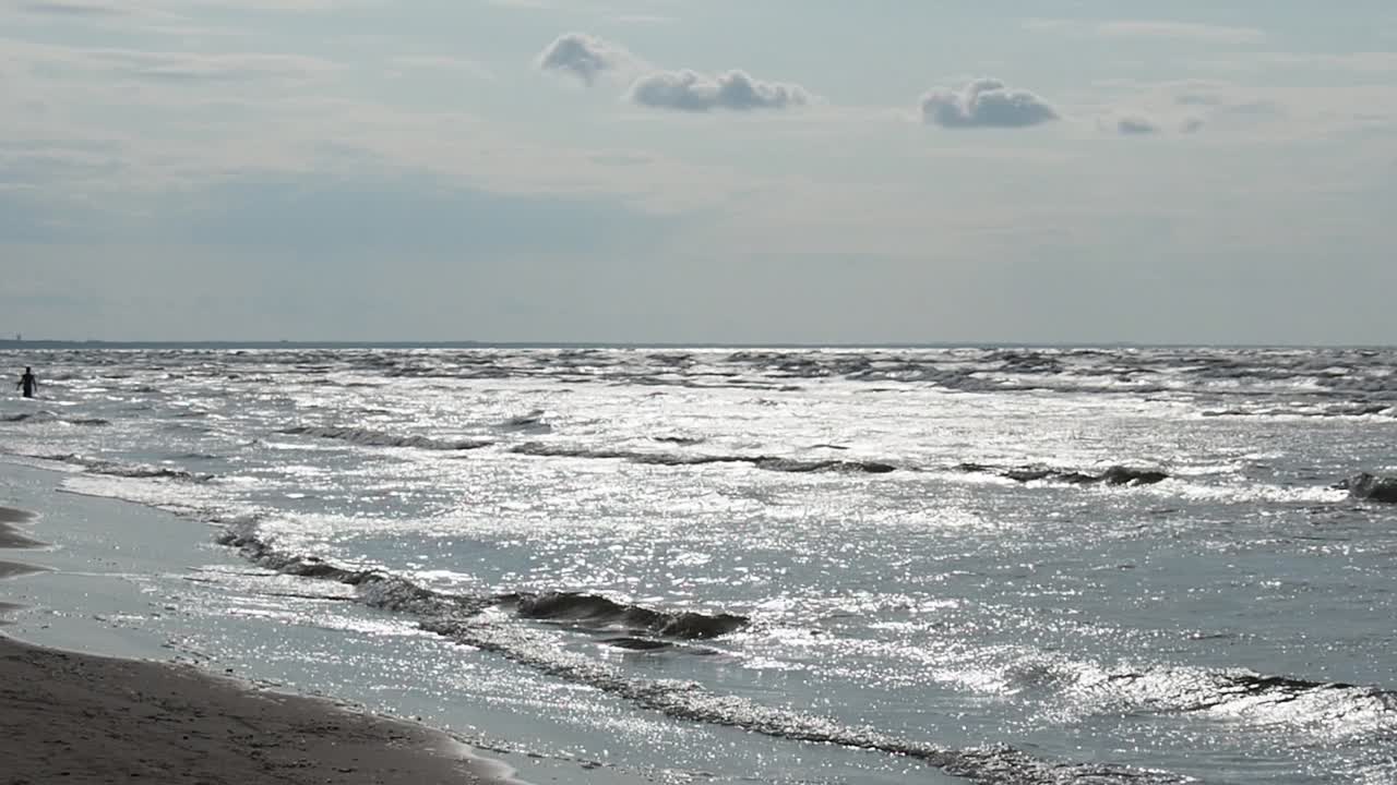 Baltic Sea on Latvian Coast. View of Waves Breaking on Sandy Beach With Sunlight Reflection