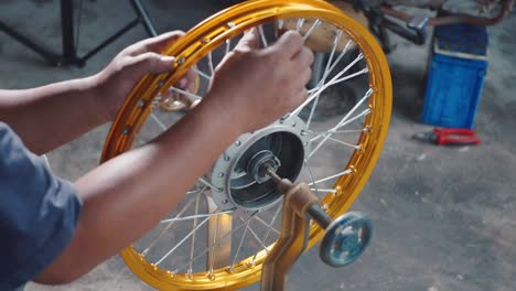 technician man working motorcycle wheel has spokes weave up on mechanic tool new steel wheel