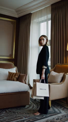 elegant woman in black suit with shopping bag in a modern hotel room