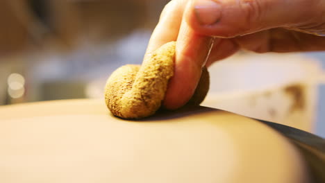 close up of male potter shaping clay for house sign on pottery turntable in ceramics studio