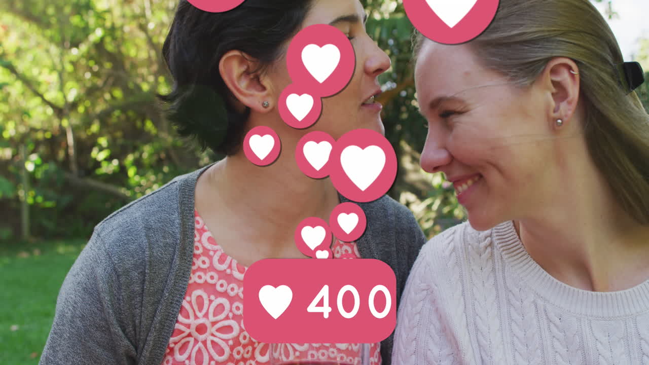 animación de emojis de corazón y números sobre una feliz pareja de mujeres caucásicas enamoradas