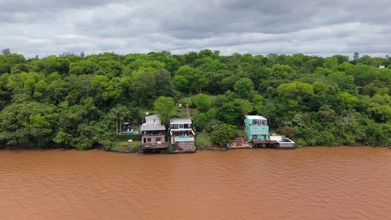 Scenic riverside houses with lush forest in Puerto Lagier, Misiones, Argentina