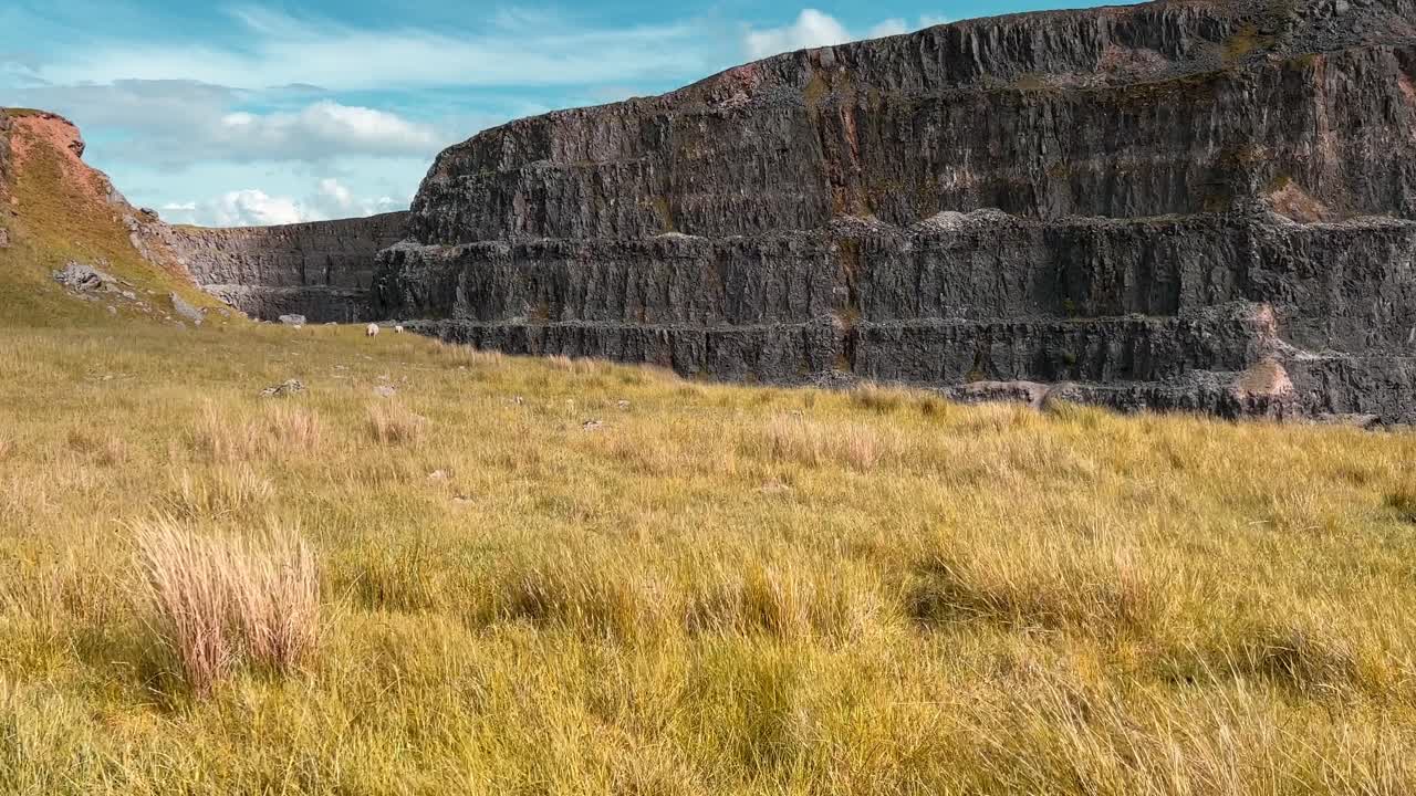 enorme desfiladero de piedra rodeado de tierras de cultivo con hierbas silvestres que soplan en el viento