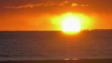 brumoso amanecer en la playa en el cielo naranja sobre las oscuras olas del océano, paisaje marino costero españa