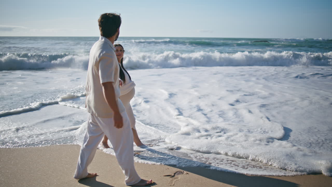 familia embarazada pisando las olas del océano en el fin de semana de verano. amantes esperando al bebé