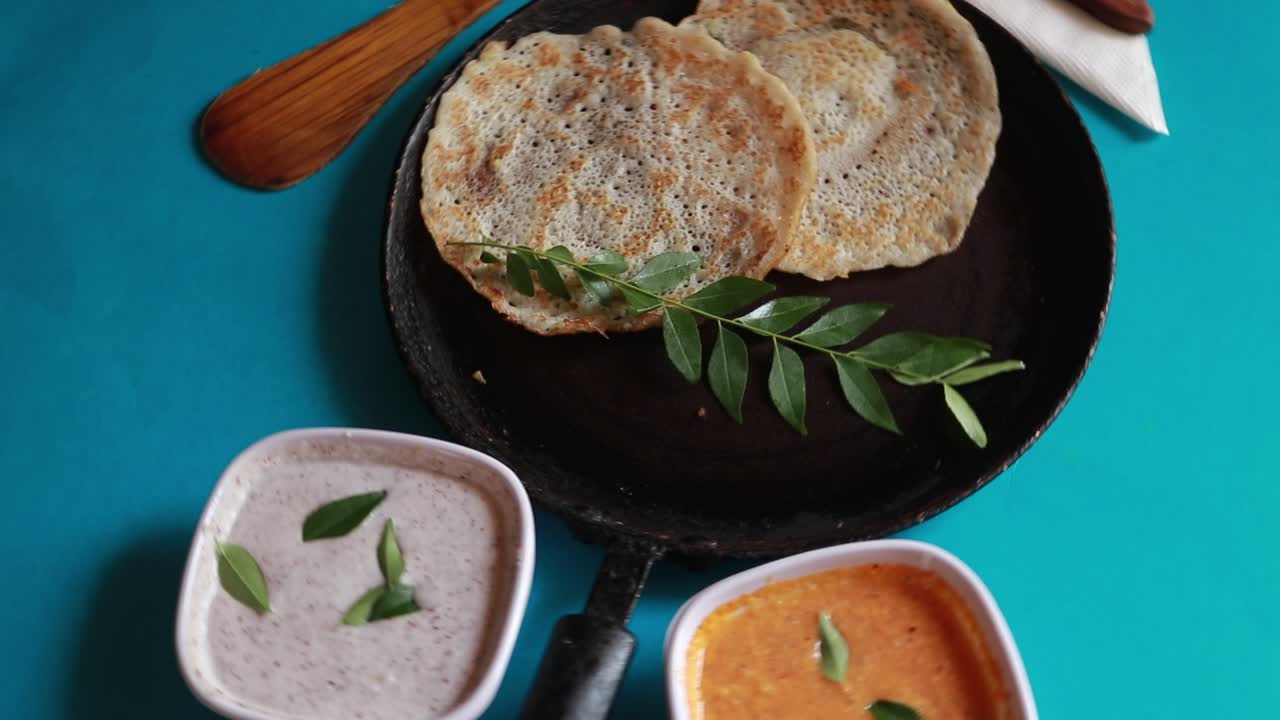 conjunto giratorio de comida del sur de la india dosa con curry y chutney sobre fondo azul