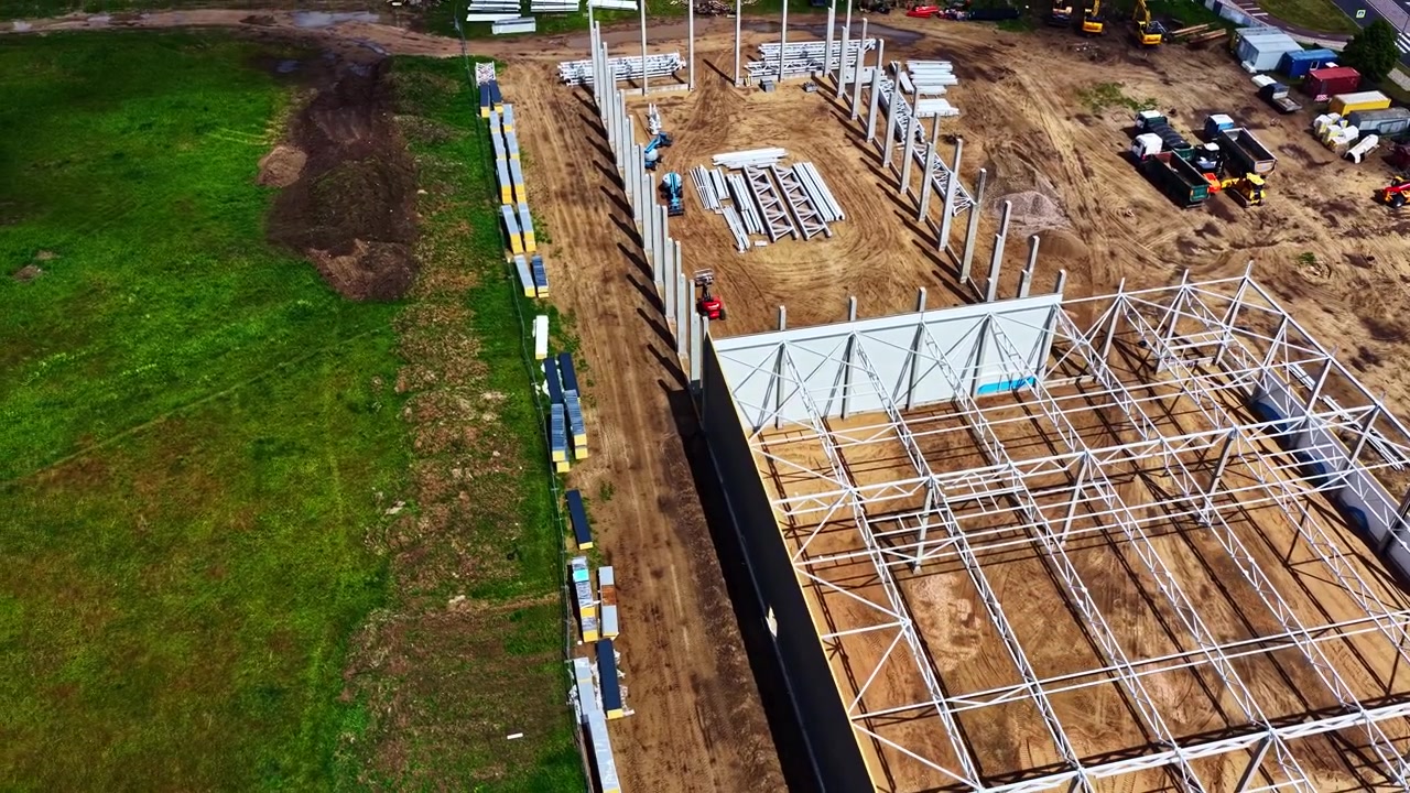 Aerial view of warehouse construction site with steel frame and concrete pillars