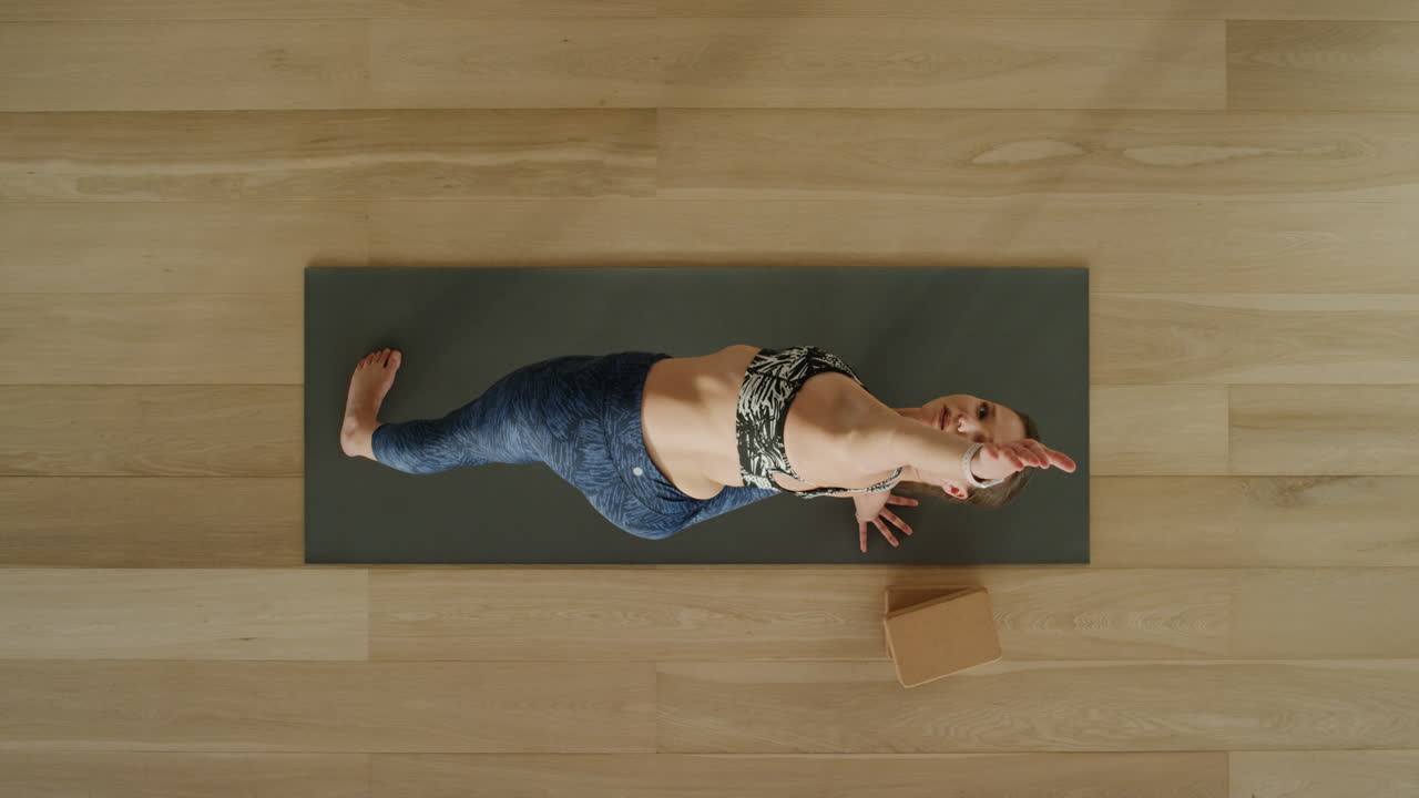 vista superior de una mujer de yoga practicando una pose de ángulo lateral extendido en un estudio de ejercicios disfrutando de un estilo de vida saludable practicando meditación en una colchoneta de ejercicios