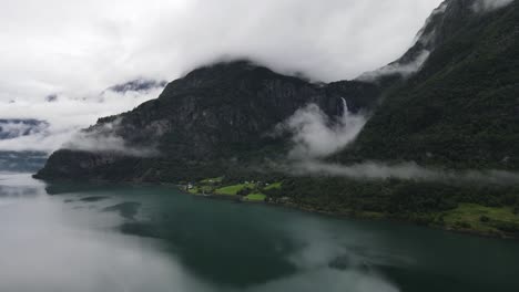 grabación de drones de una cascada detrás de un lago noruego, oculta por las nubes
