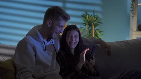 Smiling-positive-happy-couple-looking-at-funny-videos-on-social-media-on-smartphone.