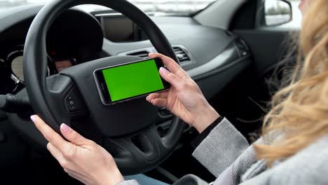 Woman sits in the modern car and using smartphone - closeup hands. Green screen.Chroma key