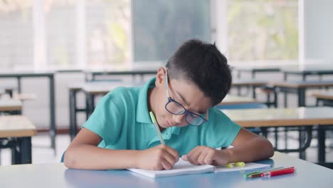 focused hispanic pupil boy wearing glasses and doing homework