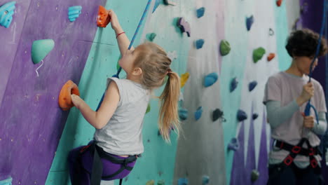 young girl rock climbing with instructor