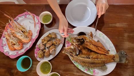 hands arranging plates of fish and shrimp on table