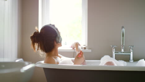 woman relaxing in a bubble bath with headphones