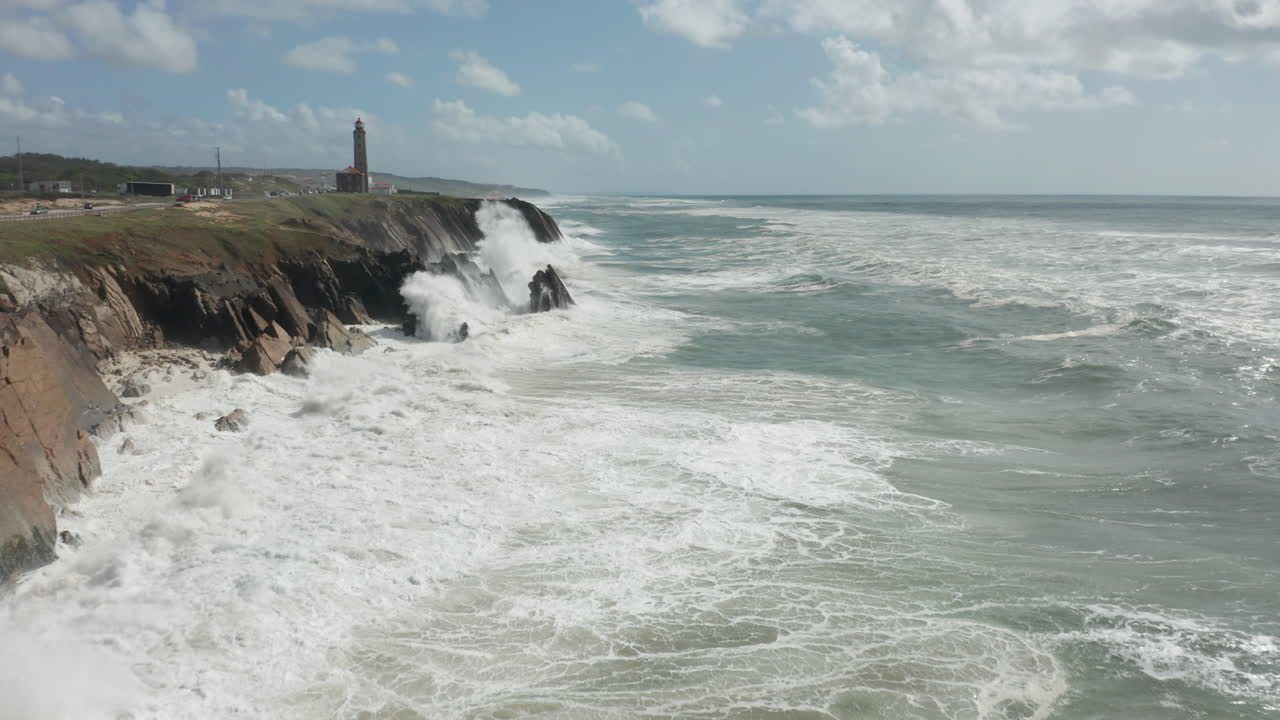 Aerial of wild sea with waves slamming on cliffs in the background