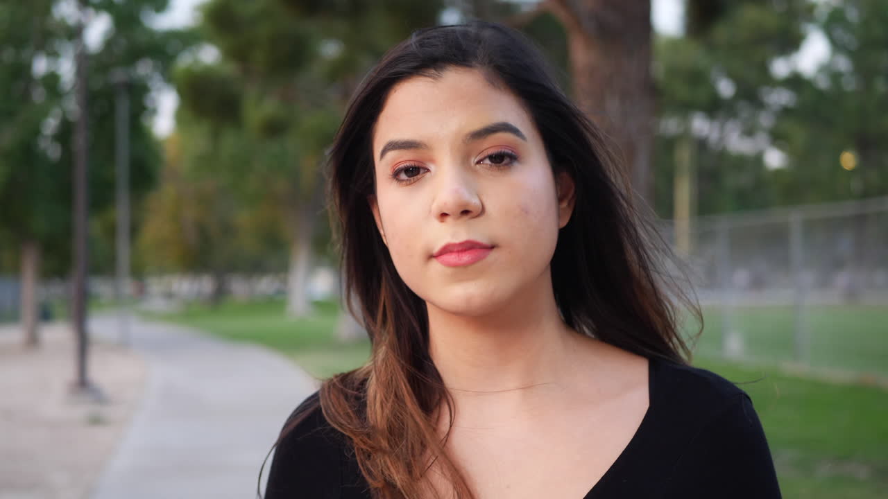 una joven y fuerte mujer hispana independiente que mira tranquila a la cámara con un estado de ánimo genuino y un sentimiento de confianza