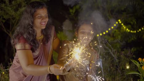 diwali celebrating a family family bursting firecrackers in diwali festival in india, mother and child enjoying with firecrackers