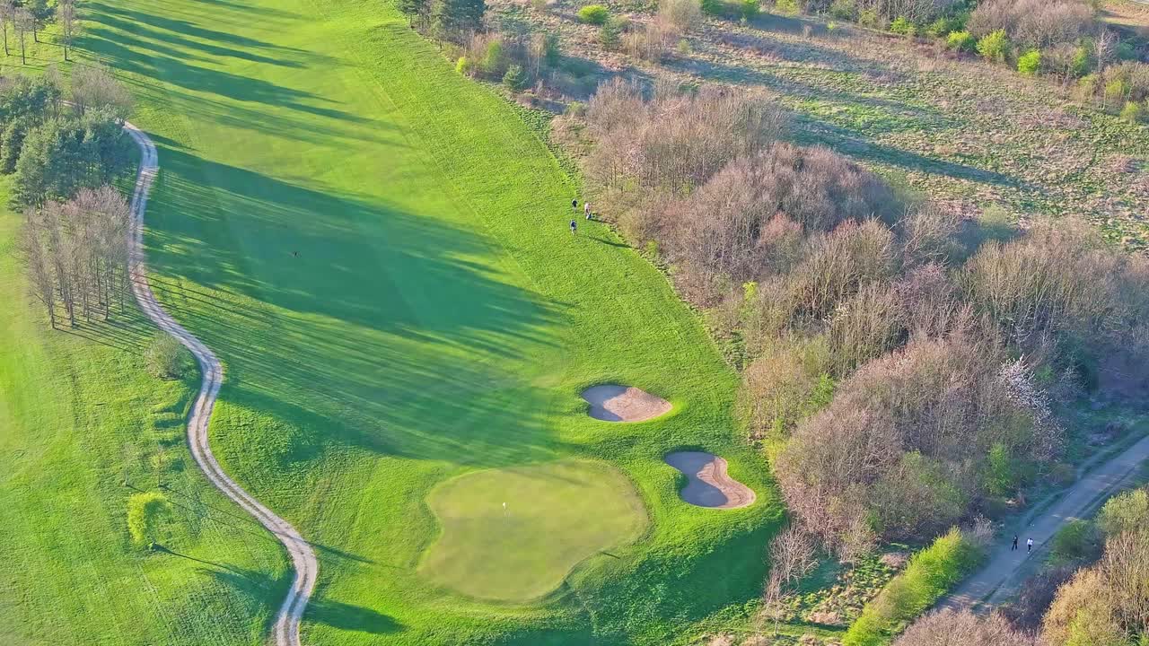 Aerial view of golfers walking down the fairway at Waterfront Golf Club, Rotherham, South Yorkshire, UK, on a sunny autumn morning