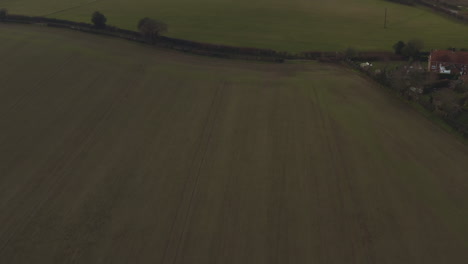 Moving forward aerial drone shot over rural fields and farmland towards a farmhouse
