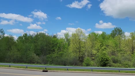 a panning shot of an asphalt road with blue sky on horizon