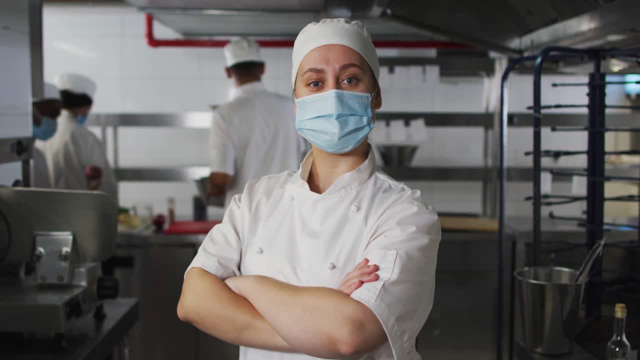 retrato de una chef caucásica que lleva una máscara facial con los brazos cruzados